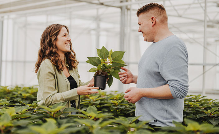 Ein Mann beret eine Frau in mitten von vielen Pflanzen