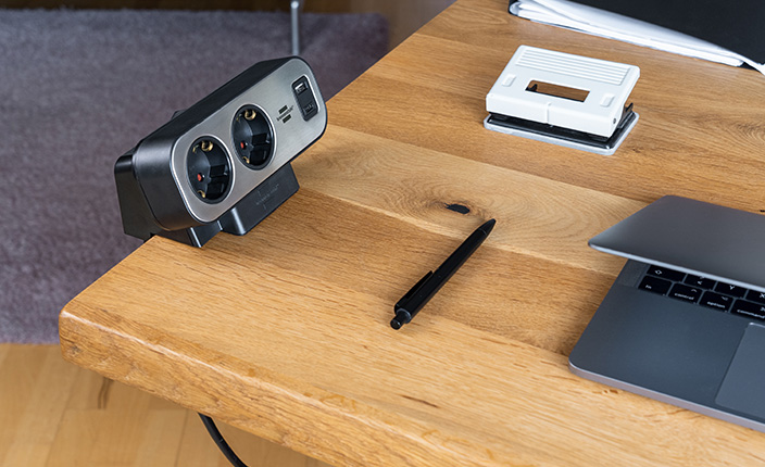 Steckdosenleiste von Brennenstuhl steht auf einem Tisch neben einem Laptop und einem Stift