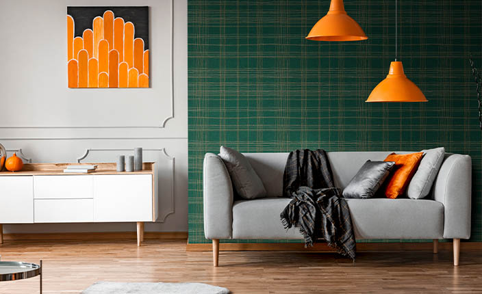 Wohnraum mit zwei klar abgetrennten Bereichen: links ein Bereich mit weißem Stuck und Sideboard, rechts eine gemütliche Sitzecke mit grüner Karotapete als Akzentwand.