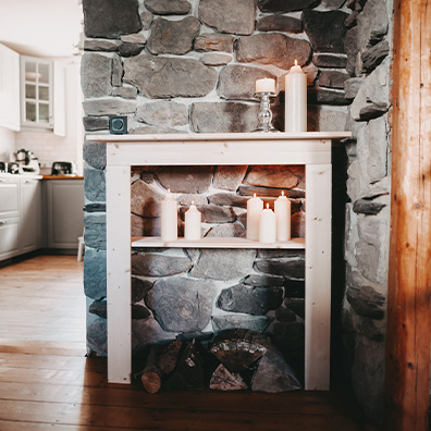 Zweigeteiltes Foto eines Deko-Kamins aus Holz vor eine Natursteinwand, dekoriert mit brennenden Kerzen, im rechten Bild wird der Kamin als Detailansicht gezeigt