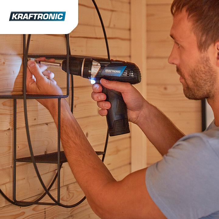Mann schraubt mit einem Akkuschreiber einen Nagel in eine Holzwand von der Marke Kraftronic