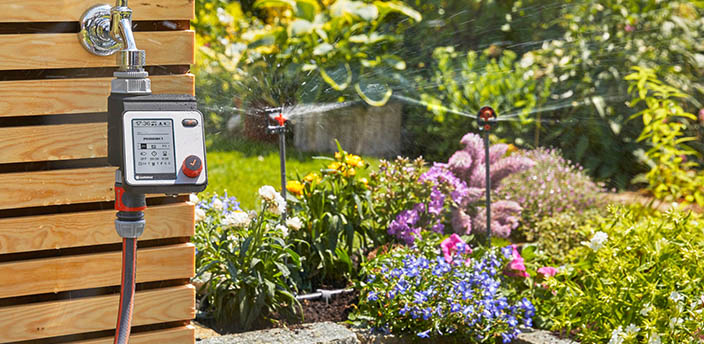 Zwei Sprinkleranlagen bewässern die Blumen in einem Garten