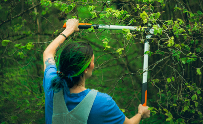 Mann schneidet Hecke mit Fiskars Heckenschere