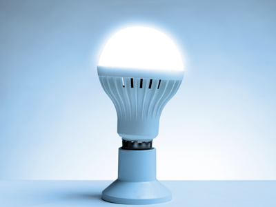 Eine moderne LED-Lampe mit Kühlrippen leuchtet hell in einem blauen Raum und steht auf einem Sockel