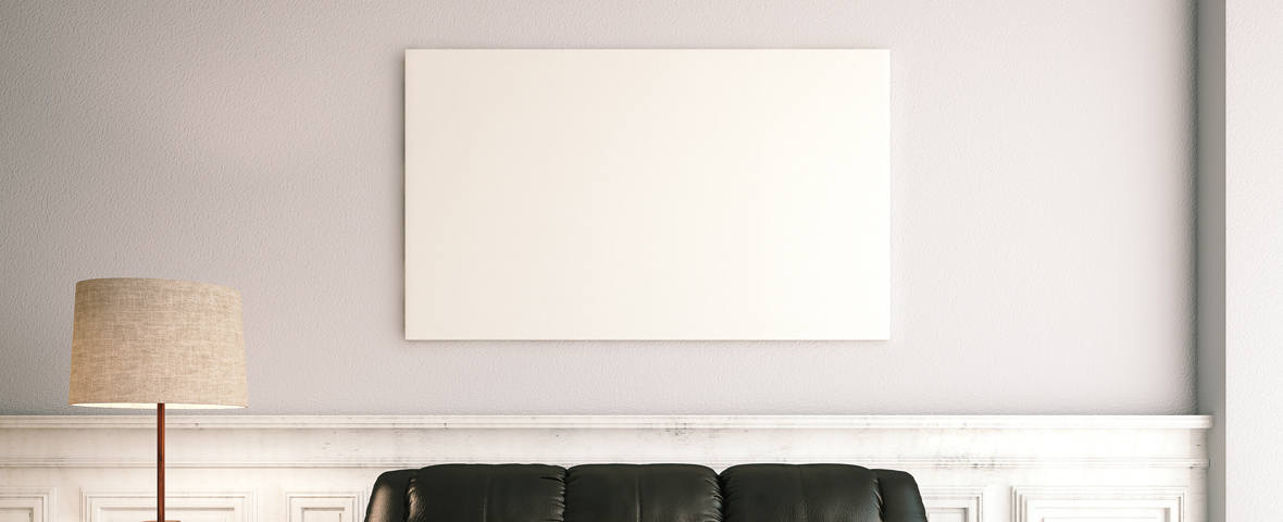 Eine flache Infrarotheizung in Form eines weißen Paneels hängt über einem schwarzen Ledersofa an der Wand