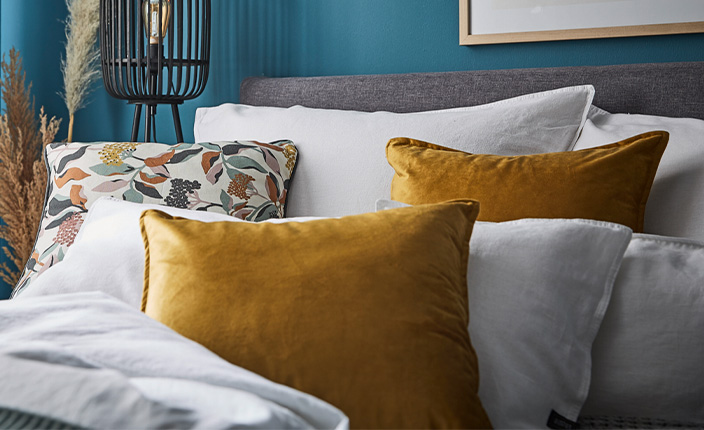 Weiße und gelbe Pölster auf einer grauen Couch angerichtet