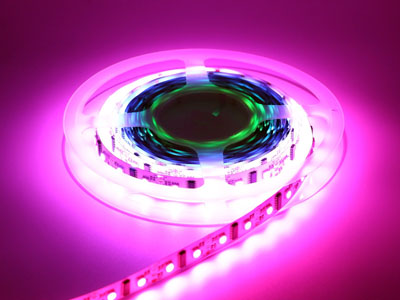 Ein aufgerolltes LED-Lichtband leuchtet in kräftigem Pink