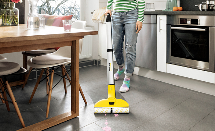 Jemand putzt den Boden einer Küche mit einem Krächer Gerät