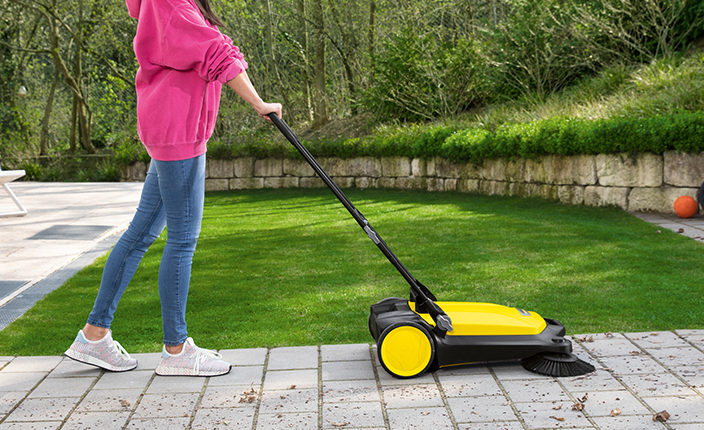 Frau verwendet ein Kärcher Gerät um den Garten sauber zu machen