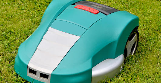 Ein grüner Mähroboter fährt über eine dichte Rasenfläche. Das Gerät mulcht den Rasenschnitt direkt und verteilt ihn gleichmäßig